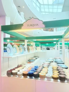 Estande da Turquia na Expo Arabia, no Mooca Plaza Shopping, com pratos decorados expostos na prateleira e pilhas de tigelas coloridas no balcão