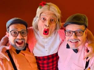 O grupo Músicos Geriatricus. Três homens caracterizados como idosos, usando óculos, perucas, boinas e maquiagem expressiva