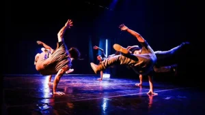 Apresentação de "Menino Assum Preto", do Flying Low. No palco, dois bailarinos fazem movimentos de break dance