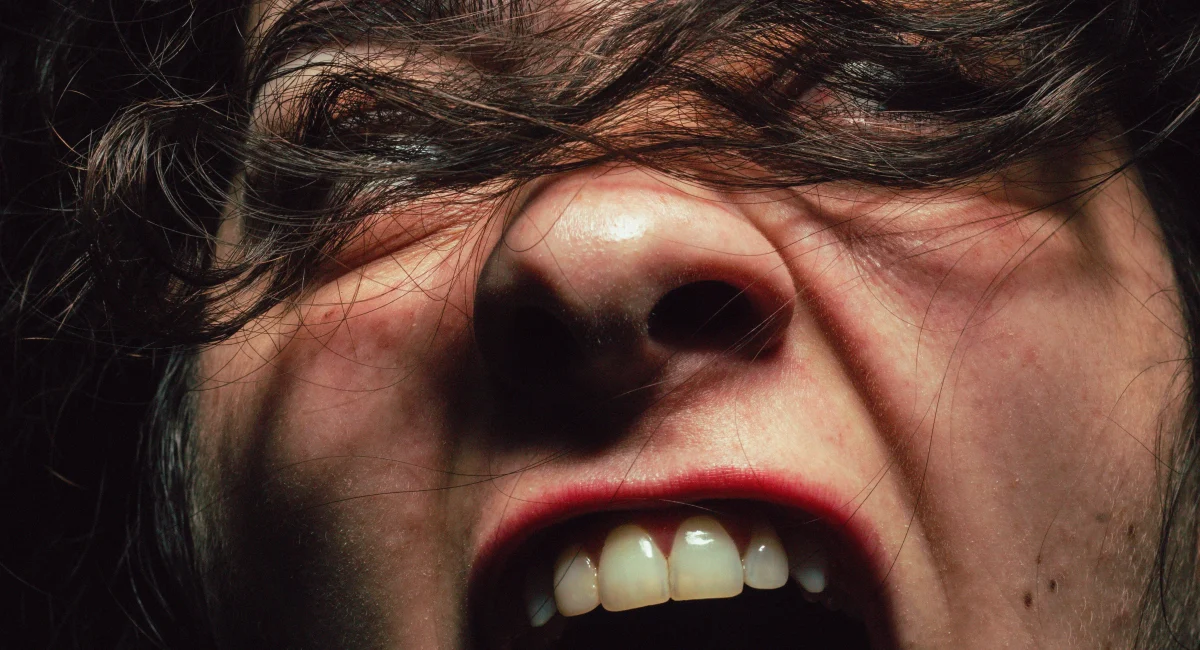 Foto de divulgação de "Revolte-se. Ela disse. Revolte-se de novo". Close-up extremo no rosto de uma mulher que grita