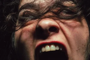 Foto de divulgação de "Revolte-se. Ela disse. Revolte-se de novo". Close-up extremo no rosto de uma mulher que grita